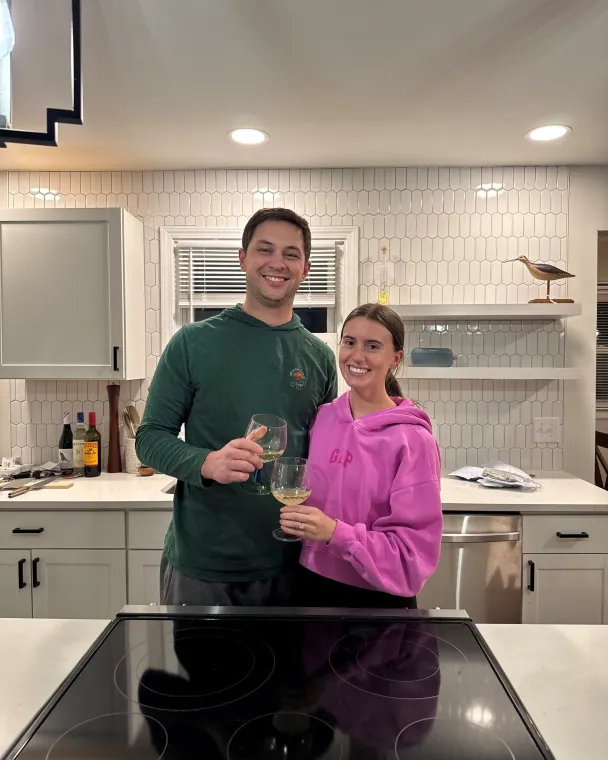 couple holding wine glasses in their kitchen
